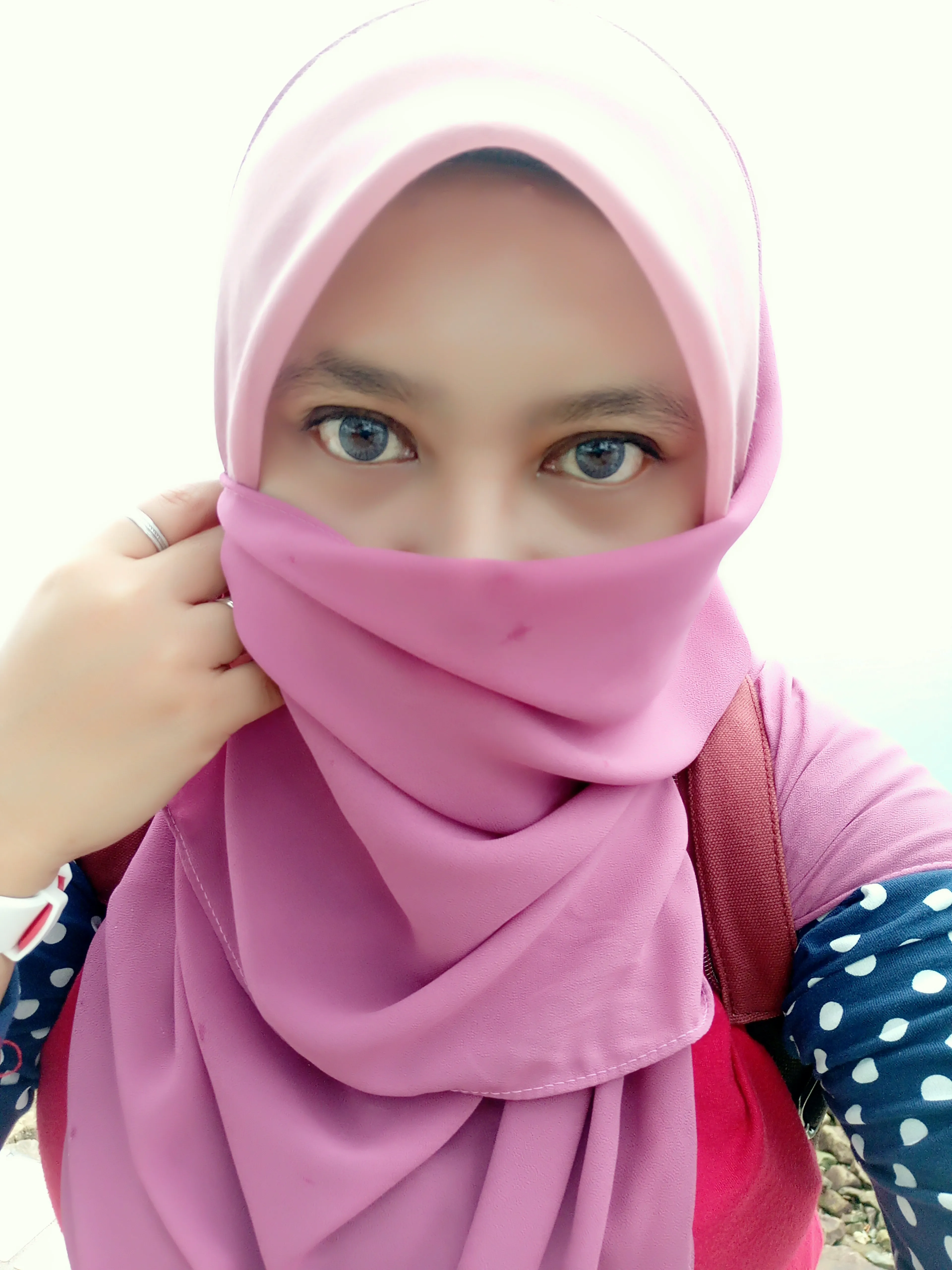 Lifestyle portrait of a person wearing a pink hijab and face covering